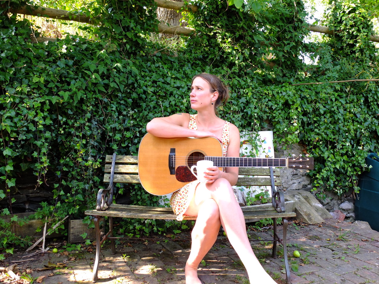 Vera van Heeringen in front f a log pile with guitar